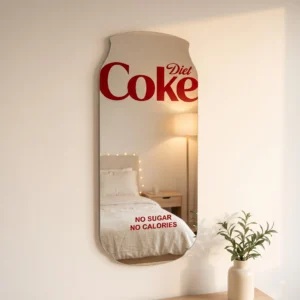 Diet Coke aesthetic wall mirror with red logo displayed in a cozy bedroom with warm lighting and minimalist decor.